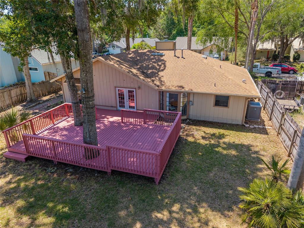 An elevated view of a house exterior featuring a large pink wooden deck with trees — 4363 NW 61ST TERRACE, GAINESVILLE, FL