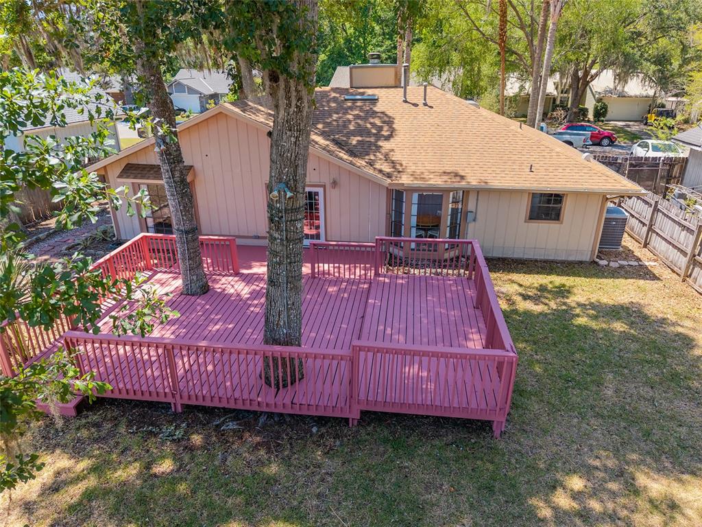 An elevated view of a house with a large pink wooden deck featuring two trees — 4363 NW 61ST TERRACE, GAINESVILLE, FL