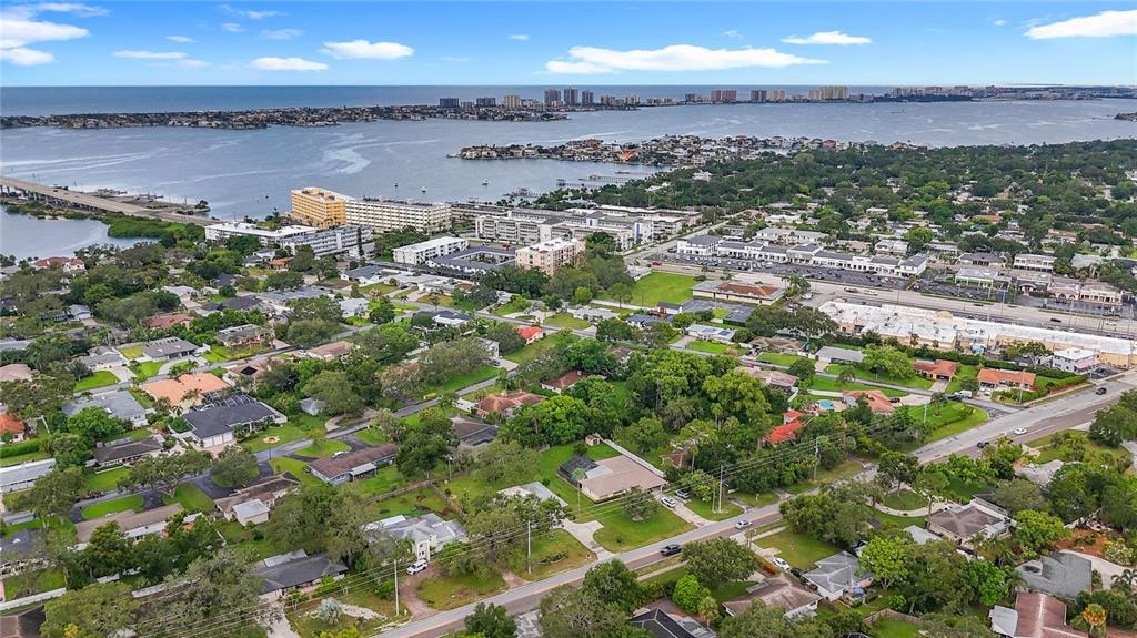An aerial view shows a residential neighborhood near a bay with a bridge and buildings — 108 INDIAN ROCKS ROAD S, BELLEAIR BLUFFS, FL