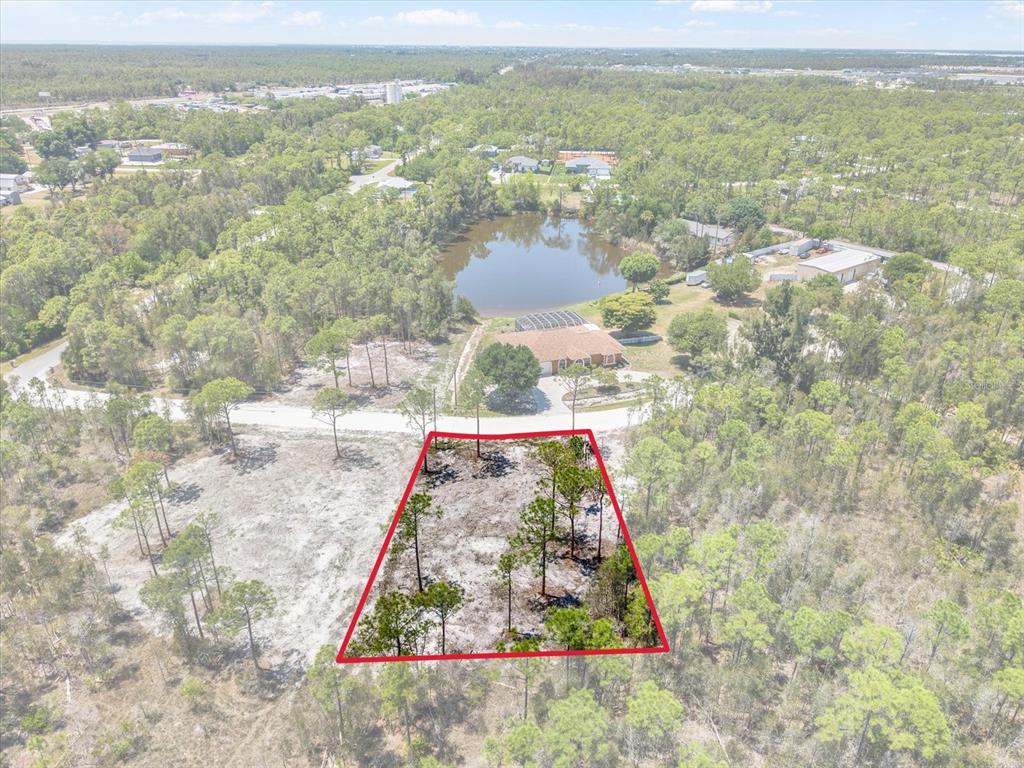An aerial view shows a vacant, partially wooded lot outlined in red near a pond — 12268 FINWICK DRIVE, PUNTA GORDA, FL