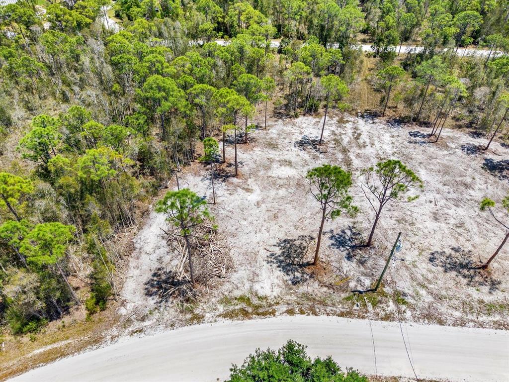 An aerial view shows a cleared, sandy residential lot bordered by trees and a road — 12268 FINWICK DRIVE, PUNTA GORDA, FL