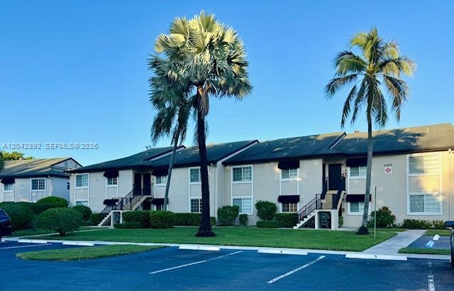 A two-story apartment building features beige stucco walls, dark shingled roofs, and tall palm trees — 4000 Crystal Lake Dr # 112, Deerfield Beach FL 33064, DEERFIELD BEACH, FL