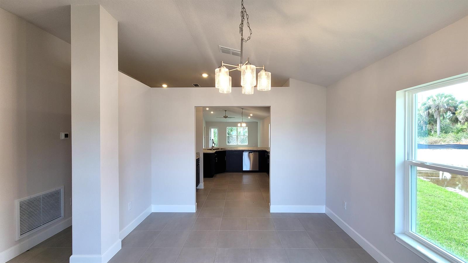 A dining area with tile floors and a chandelier leads into a kitchen with dark cabinets — 8839 Waterstone Boulevard, Fort Pierce FL 34951, FORT PIERCE, FL