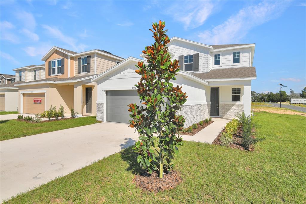 A two-story house with a white exterior, stone accents, and a gray garage door — 6195 SW 64TH TERRACE, OCALA, FL