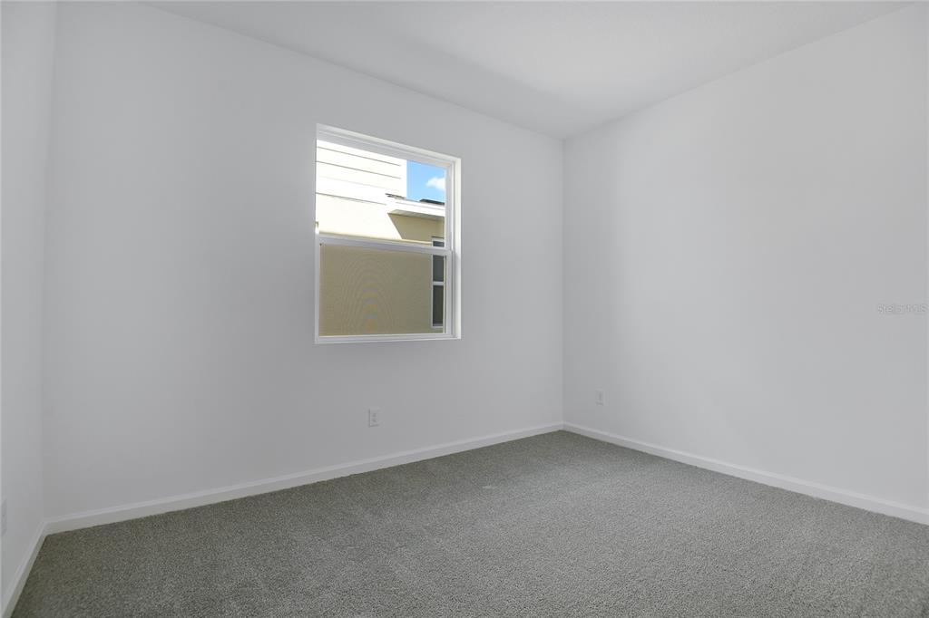 An empty bedroom features white walls, gray carpeting, and a single window — 6195 SW 64TH TERRACE, OCALA, FL