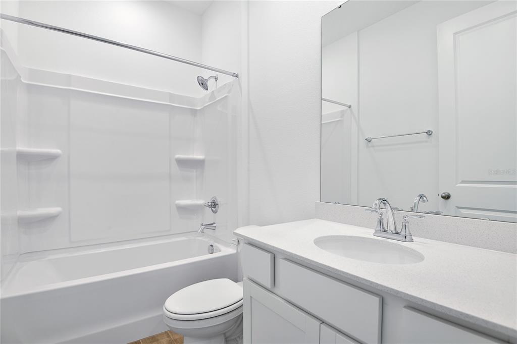 A bathroom features a white vanity, a toilet, and a shower-tub combination with white walls — 6195 SW 64TH TERRACE, OCALA, FL
