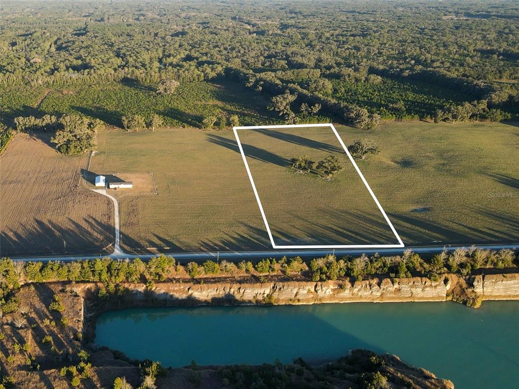 An aerial view shows a rectangular plot of land outlined in white near a lake — 004 NW 202ND STREET, NEWBERRY, FL