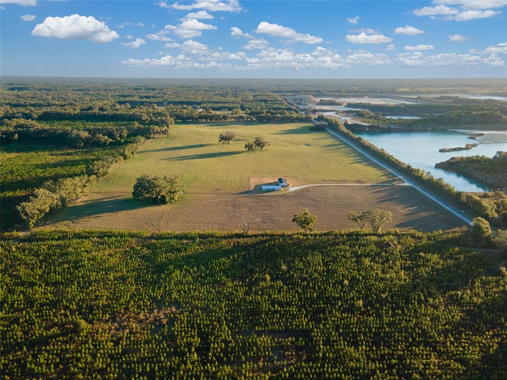 An aerial view shows a rural property with a house, open fields, and a lake — 004 NW 202ND STREET, NEWBERRY, FL