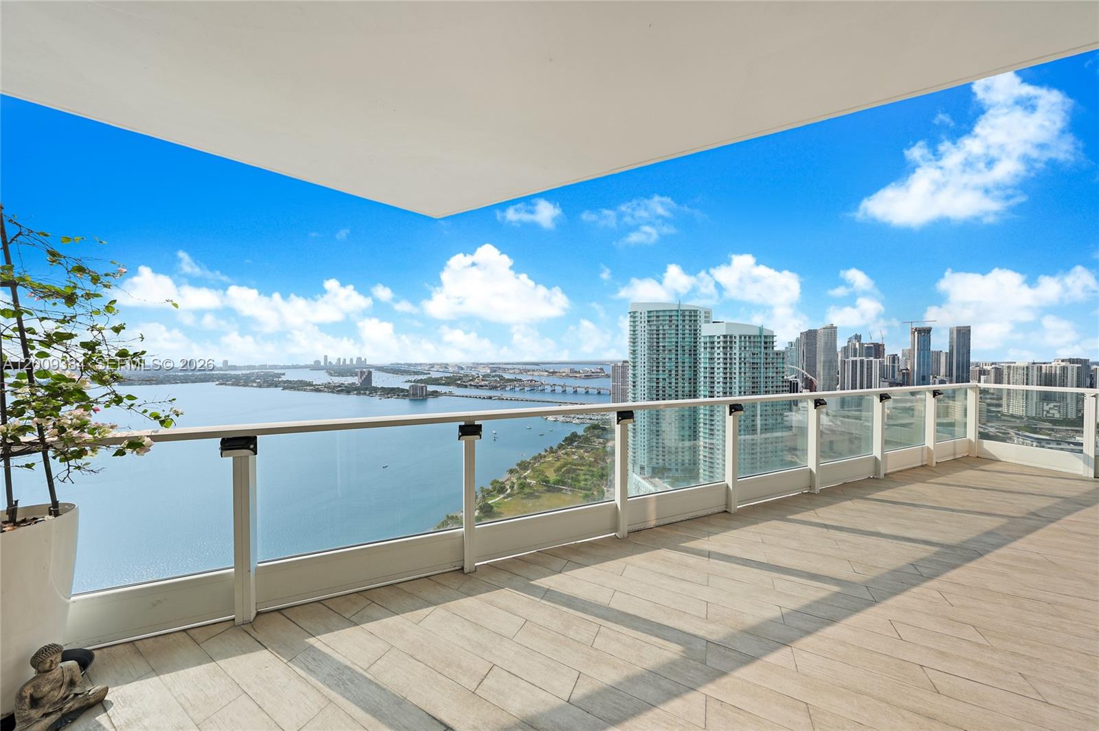 A balcony with glass railings overlooks a bay, a bridge, and a city skyline — 2020 N Bayshore Dr # 3902, Miami FL 33137, MIAMI, FL
