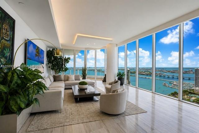 A modern living room features floor-to-ceiling windows overlooking a bay with a bridge — 2020 N Bayshore Dr # 3902, Miami FL 33137, MIAMI, FL
