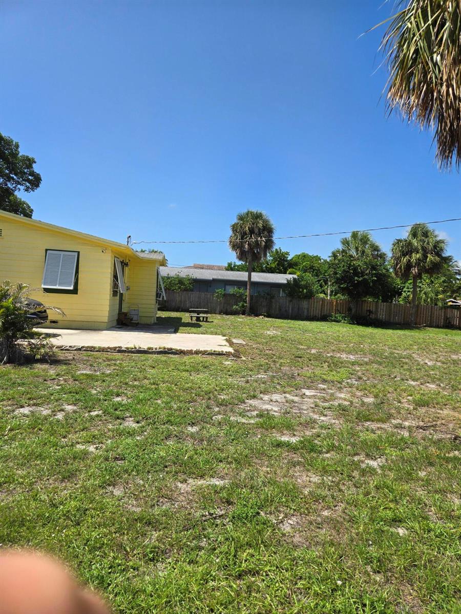 The exterior of a yellow house features a concrete patio and a large grassy yard — 239 NE 18th Avenue, Pompano Beach FL 33060, POMPANO BEACH, FL