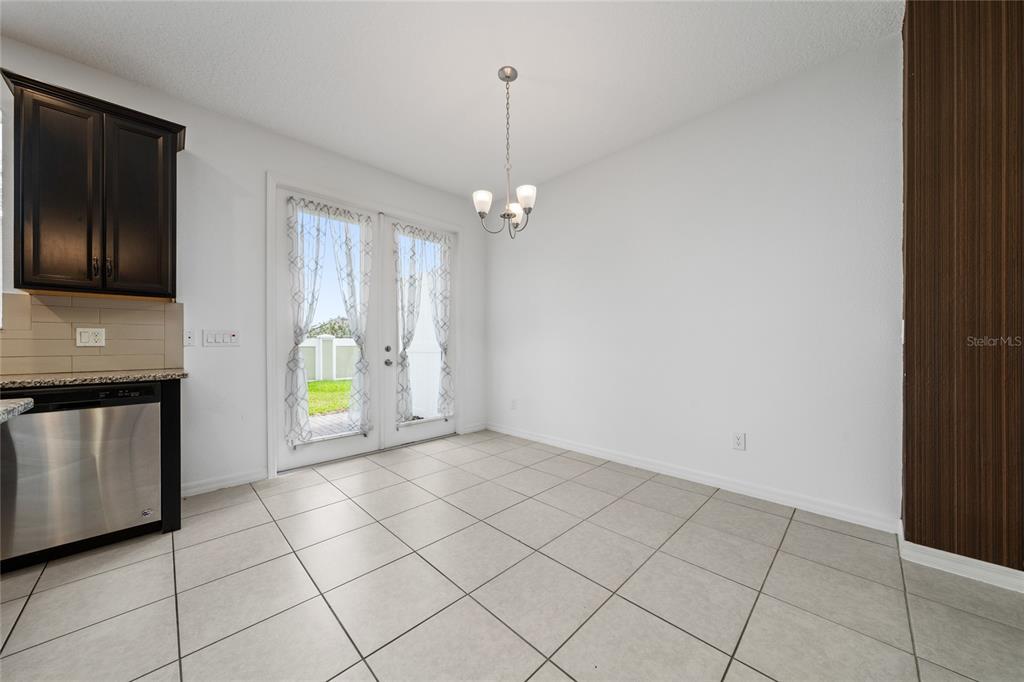 A dining area features tile flooring, a chandelier, and glass doors leading to a patio — 2588 SEDGE GRASS WAY, ORLANDO, FL