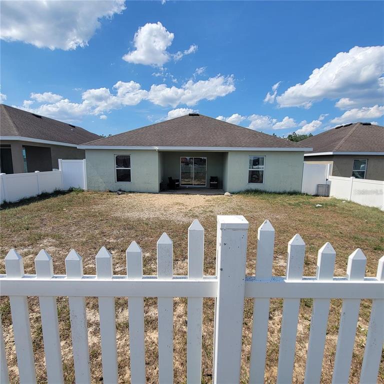 The exterior view shows the back of a house with a covered patio and yard — 30990 SATINLEAF RUN, BROOKSVILLE, FL