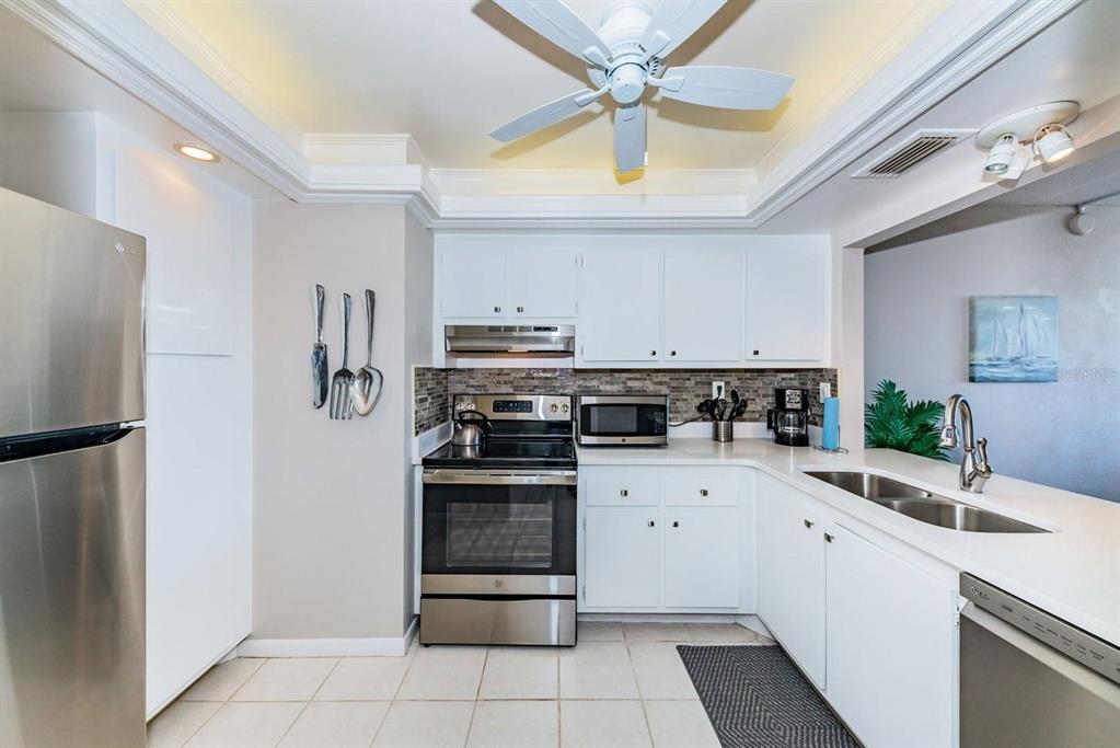 A kitchen features white cabinetry, stainless steel appliances, a ceiling fan, and tiled flooring — 6219 PALMA BOULEVARD S UNIT 305, ST PETERSBURG, FL