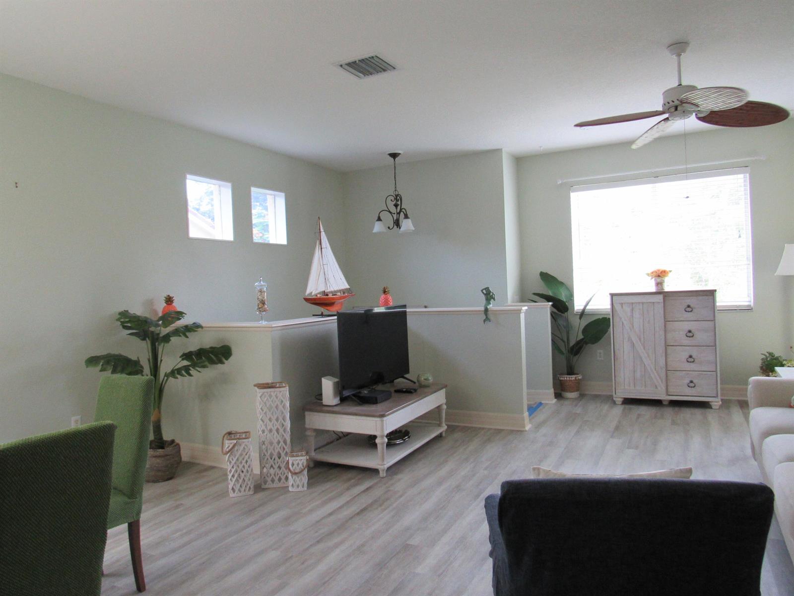 A living room features light green walls, wood-look flooring, a ceiling fan, and a television — 48 SE Sedona Circle # 201, Stuart FL 34994, STUART, FL