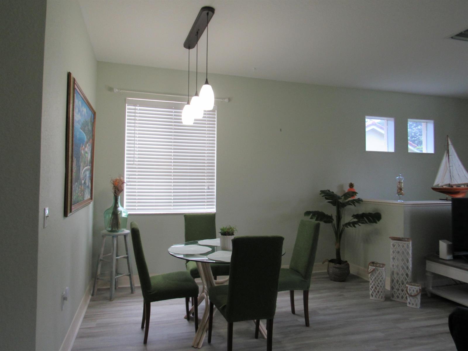 A dining area features a glass-topped table, four green chairs, and a three-light pendant fixture — 48 SE Sedona Circle # 201, Stuart FL 34994, STUART, FL