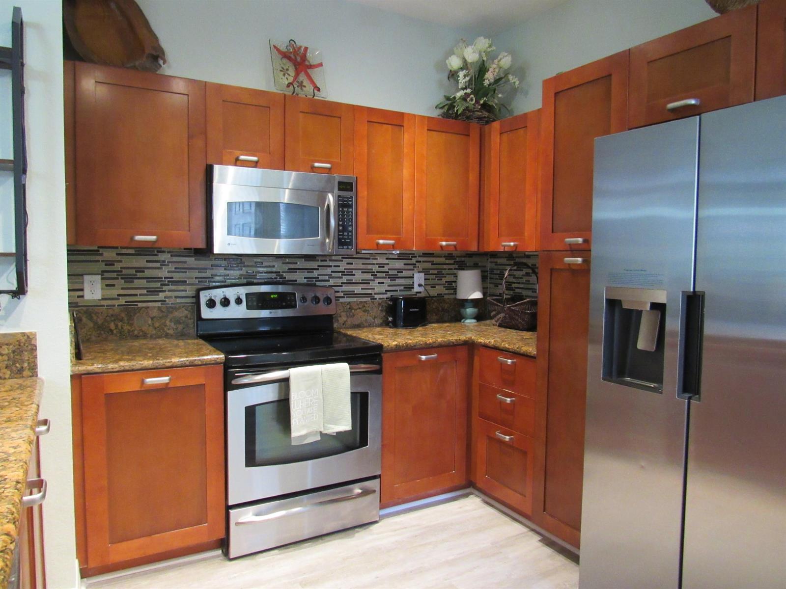 A kitchen with wood cabinets, stainless steel appliances, and a mosaic tile backsplash — 48 SE Sedona Circle # 201, Stuart FL 34994, STUART, FL