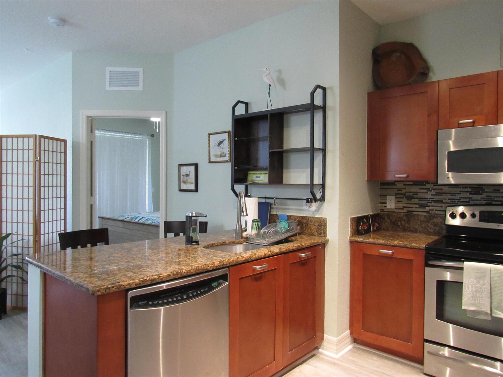 A kitchen with wood cabinets, granite countertops, stainless steel appliances, and a breakfast bar — 48 SE Sedona Circle # 201, Stuart FL 34994, STUART, FL