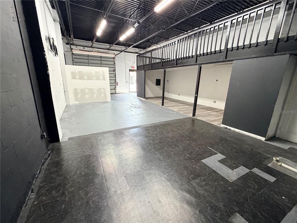 An industrial-style commercial space features a mezzanine, concrete floors, and a roll-up garage door — 6102 E ADAMO DRIVE, TAMPA, FL