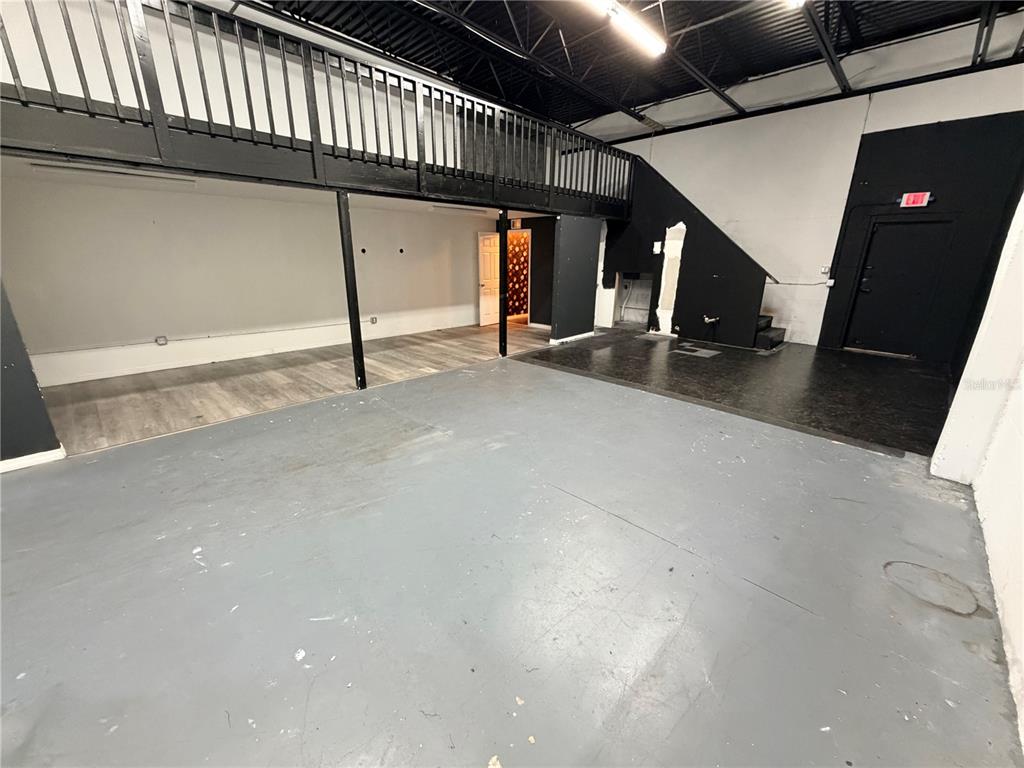 An industrial-style interior features a concrete floor, a black metal loft railing, and a staircase — 6102 E ADAMO DRIVE, TAMPA, FL