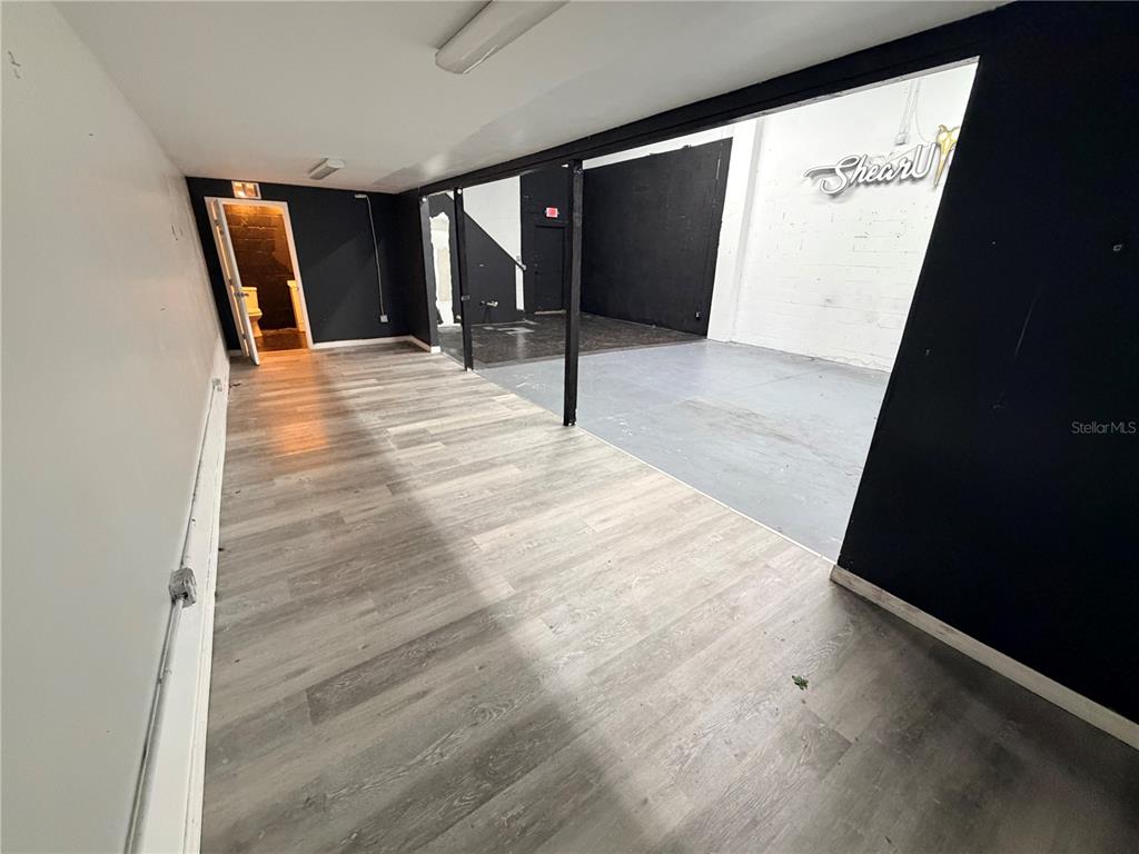 A commercial space features wood-look flooring, black accent walls, and a separate partitioned area — 6102 E ADAMO DRIVE, TAMPA, FL