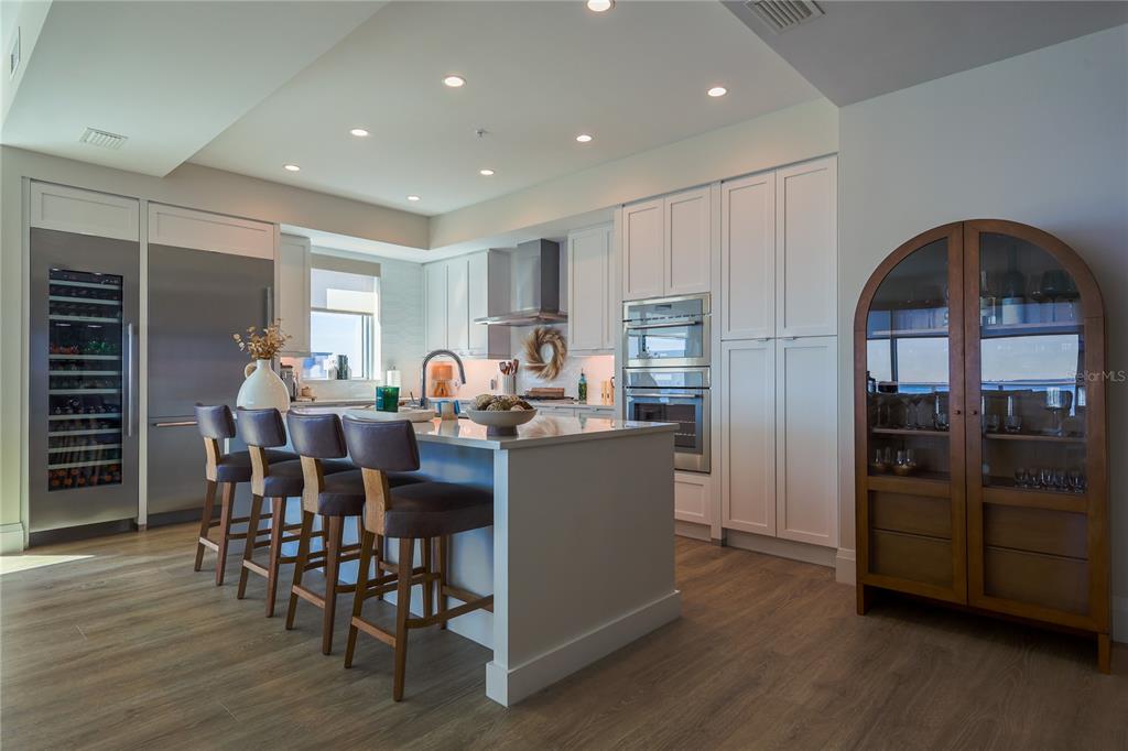 A modern kitchen features white cabinetry, a central island with bar seating, and stainless appliances — 2910 W BARCELONA STREET UNIT 604, TAMPA, FL