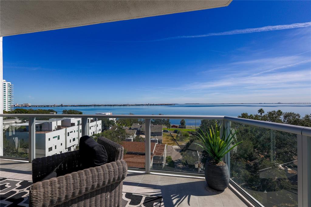 A balcony with a wicker chair and potted plant overlooks a large body of water — 2910 W BARCELONA STREET UNIT 604, TAMPA, FL