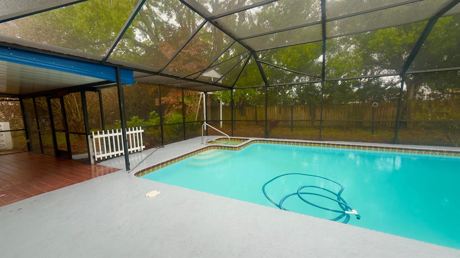 A screened-in swimming pool and spa with a concrete deck and a wooden fence — 4221 Rose Lane NE, Fort Pierce FL 34982, FORT PIERCE, FL