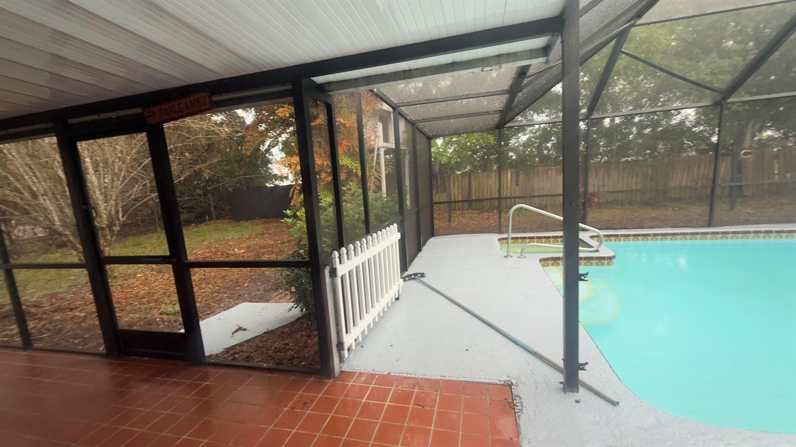 A screened-in patio features a tiled floor, a small white fence, and a swimming pool — 4221 Rose Lane NE, Fort Pierce FL 34982, FORT PIERCE, FL