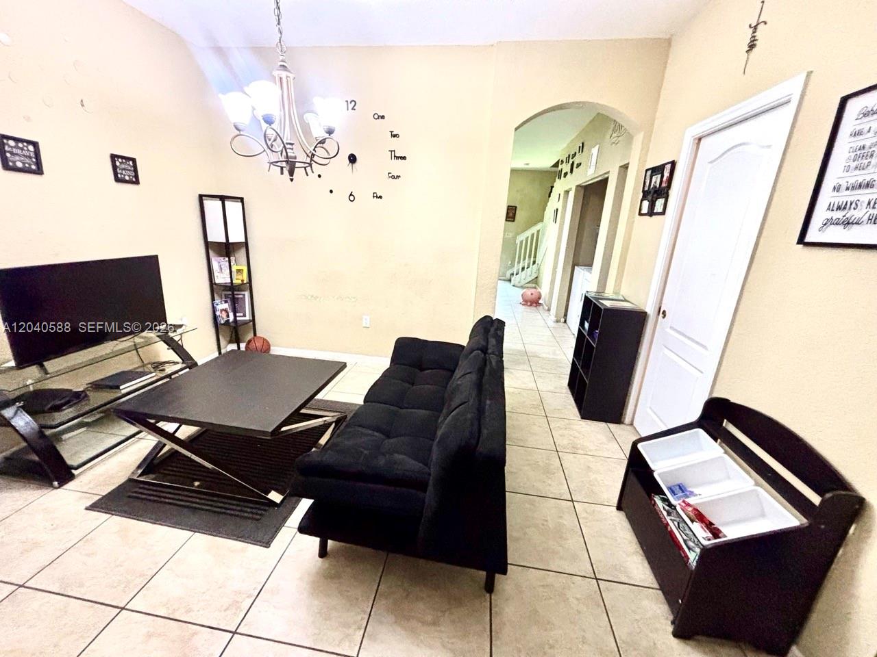 A living room features a black sofa, a glass-topped coffee table, and tile flooring — MIAMI GARDENS, FL