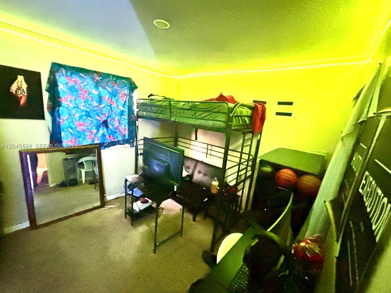 A bedroom features a loft bed over a desk and a large floor mirror — MIAMI GARDENS, FL