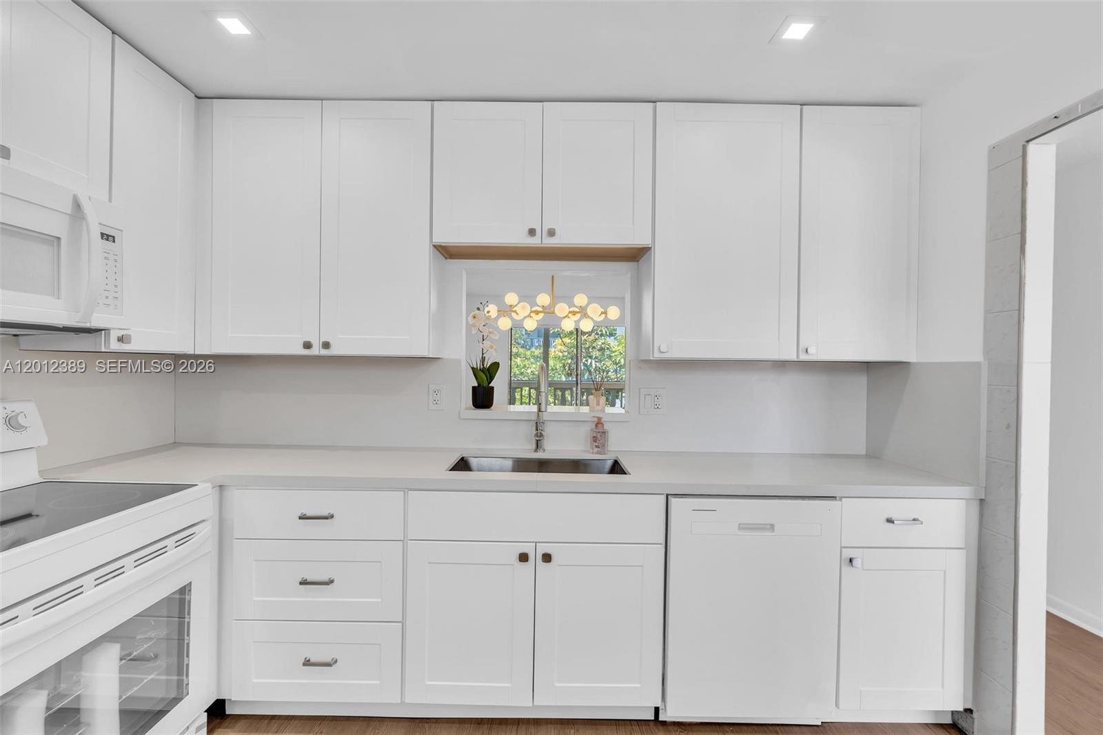 A kitchen features white shaker cabinets, a stainless steel sink, and a window view — 218 NE 12th Ave # 302, Hallandale Beach FL 33009, HALLANDALE BEACH, FL