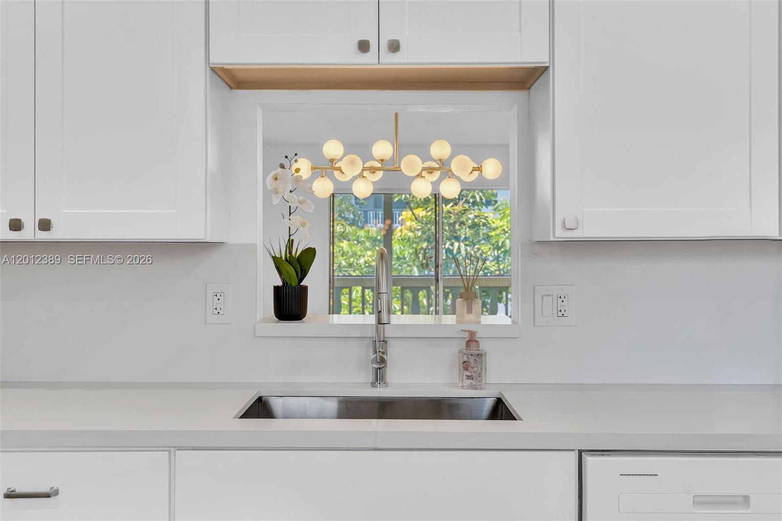 A kitchen sink is centered below a window with a modern light fixture above — 218 NE 12th Ave # 302, Hallandale Beach FL 33009, HALLANDALE BEACH, FL