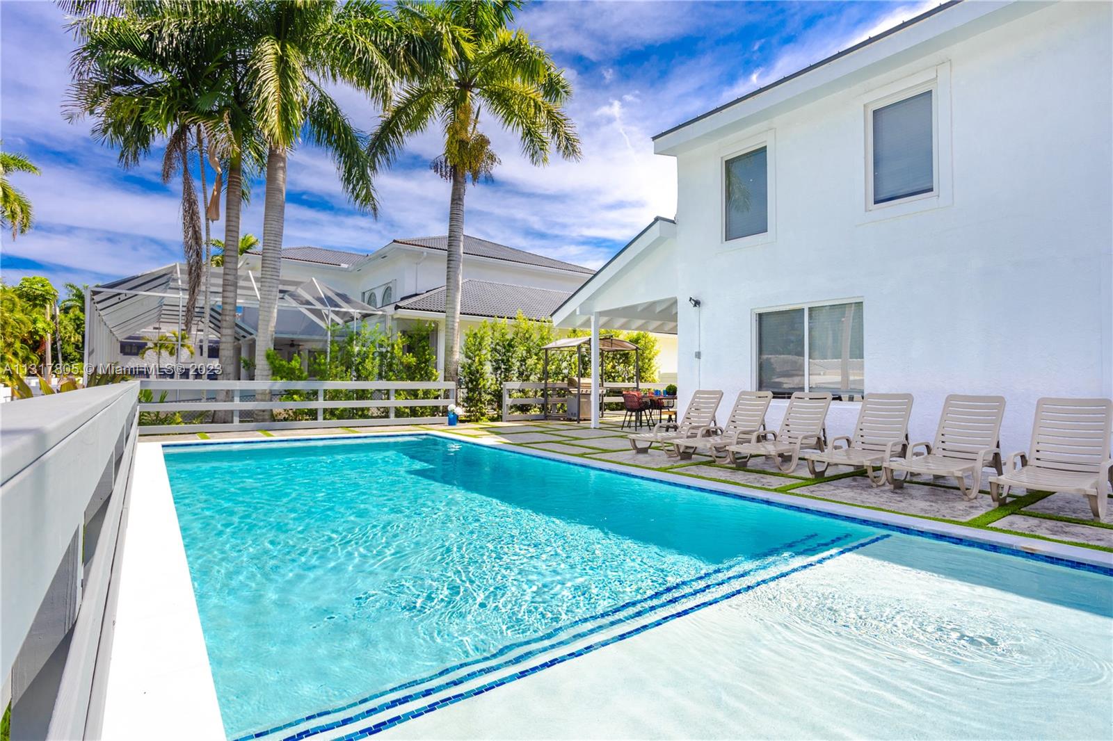 A swimming pool sits beside a white house with several lounge chairs on the patio — 1109 Hollywood Blvd, Hollywood FL 33019, HOLLYWOOD, FL