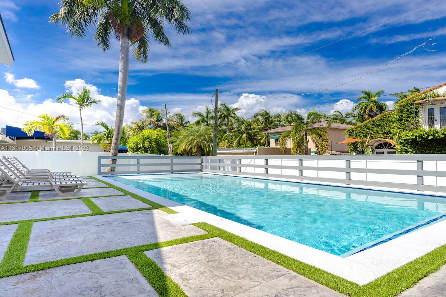 A rectangular swimming pool is surrounded by a stone patio with artificial turf accents — 1109 Hollywood Blvd, Hollywood FL 33019, HOLLYWOOD, FL