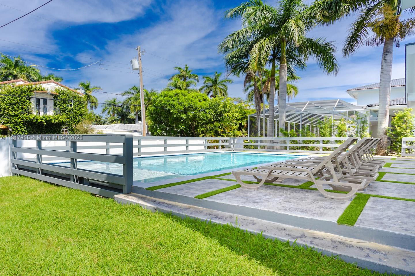 A swimming pool with lounge chairs on a patio surrounded by a white fence — 1109 Hollywood Blvd, Hollywood FL 33019, HOLLYWOOD, FL