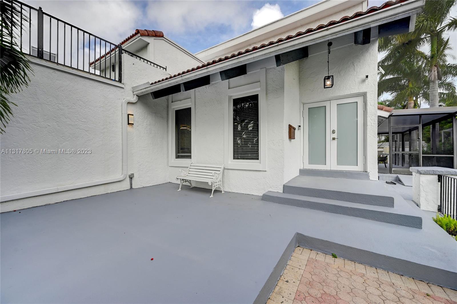 A white stucco house exterior features a gray patio, a bench, and double glass doors — 1109 Hollywood Blvd, Hollywood FL 33019, HOLLYWOOD, FL