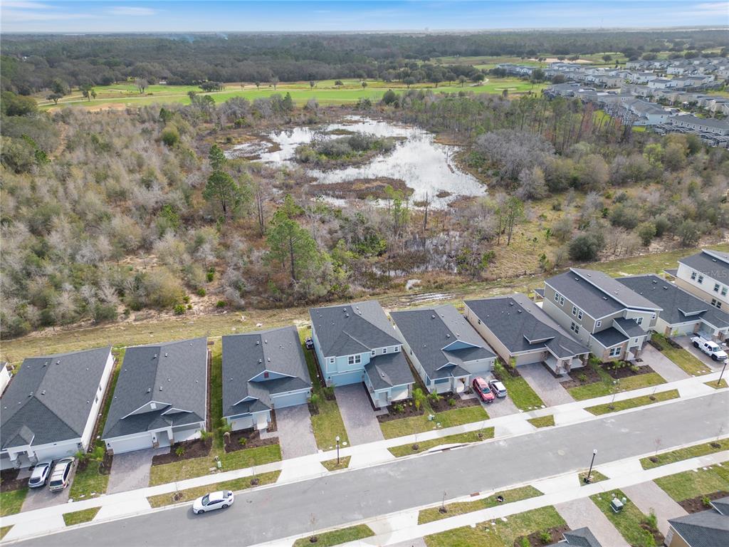 An aerial view shows a row of suburban houses bordering a wooded wetland area — 157 ACES HIGH LANE, DAVENPORT, FL