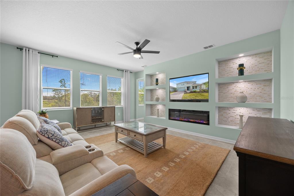 A living room features a built-in fireplace, shelving, a beige sofa, and a coffee table — 157 ACES HIGH LANE, DAVENPORT, FL
