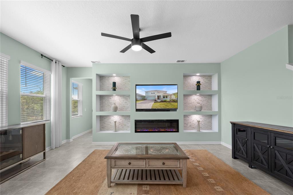 A living room features a built-in media wall with a fireplace, shelves, and a ceiling fan — 157 ACES HIGH LANE, DAVENPORT, FL