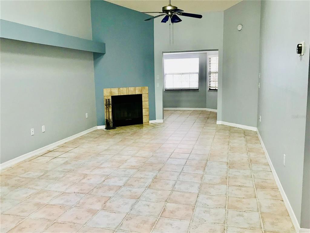 A living room features a tiled floor, a fireplace with a tiled surround, and a ceiling fan — 10425 LA MIRAGE COURT UNIT 202, TAMPA, FL