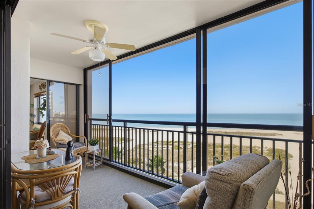 A balcony with a ceiling fan, wicker furniture, and a view of the beach — 1270 GULF BOULEVARD UNIT 801, CLEARWATER BEACH, FL