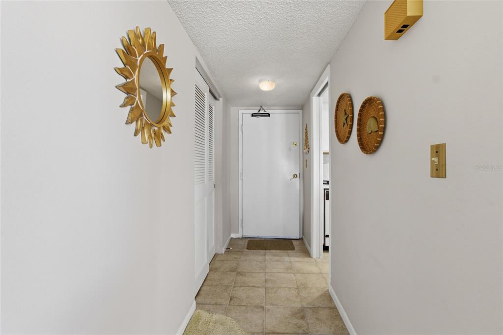 A tiled entryway features a white door, a louvered closet, and decorative wall hangings — 1270 GULF BOULEVARD UNIT 801, CLEARWATER BEACH, FL
