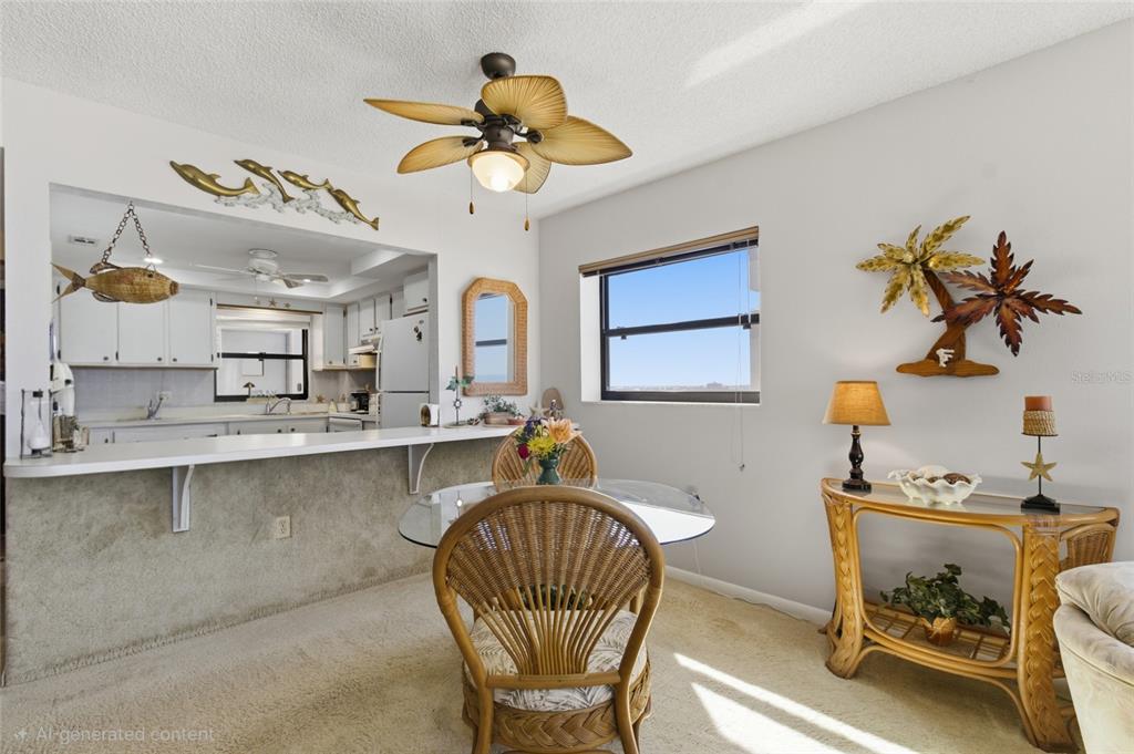 A dining area with a glass table, wicker chairs, and a breakfast bar overlooking a kitchen — 1270 GULF BOULEVARD UNIT 801, CLEARWATER BEACH, FL