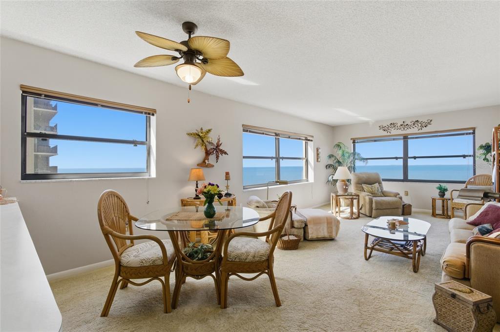 A living and dining area with wicker furniture, a ceiling fan, and ocean views — 1270 GULF BOULEVARD UNIT 801, CLEARWATER BEACH, FL