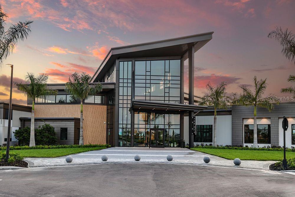 A modern building with a glass facade, metal roof, and palm trees at sunset — 5410 CROWN POINT ROAD, KISSIMMEE, FL