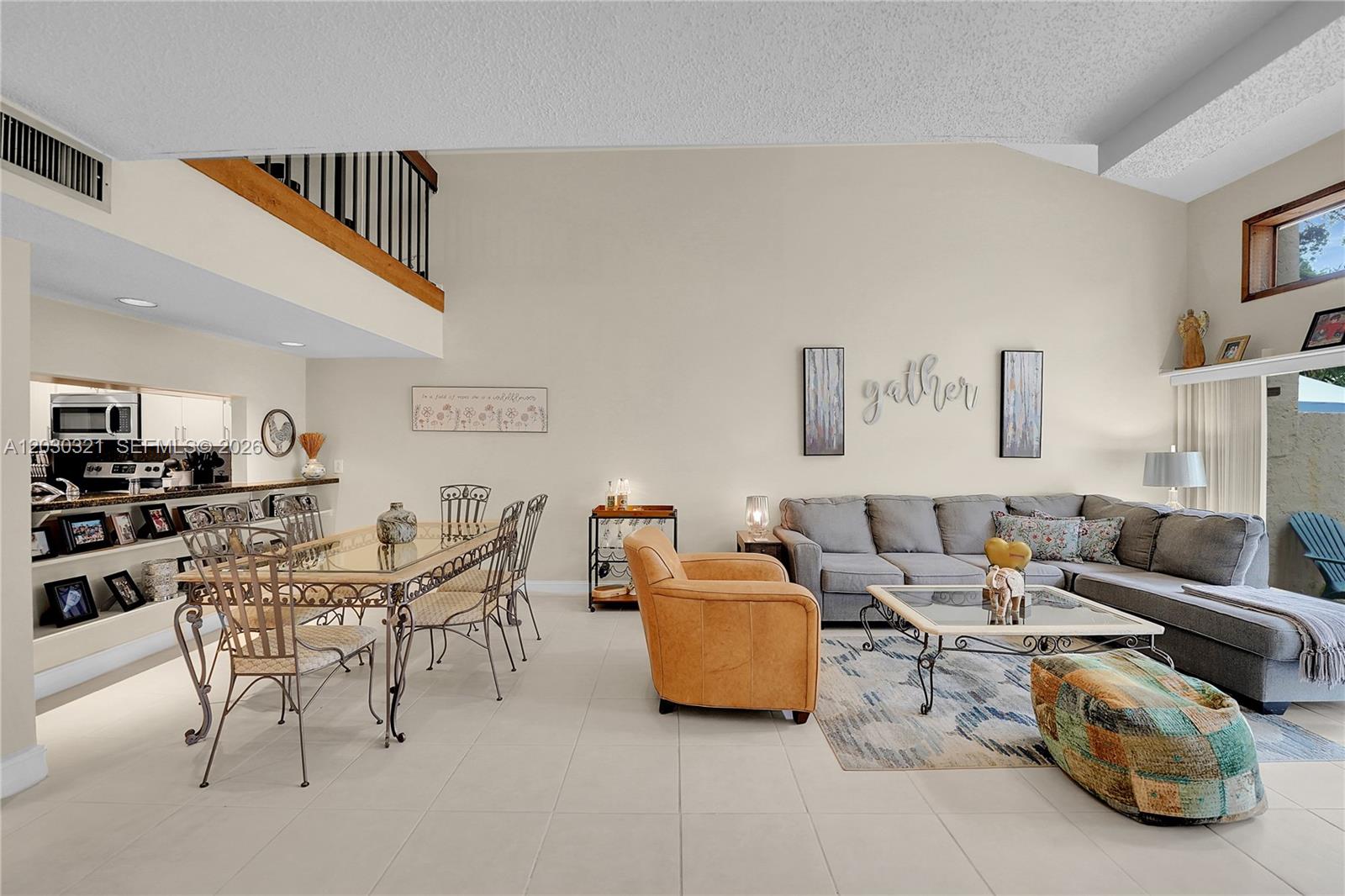 A bright, open-concept living and dining area features vaulted ceilings, tile flooring, and neutral walls — 1400 NW 9th Ave # 18, Boca Raton FL 33486, BOCA RATON, FL