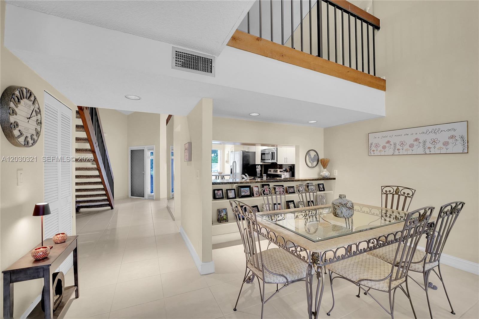 A dining area with a glass table and chairs sits near a kitchen pass-through window — 1400 NW 9th Ave # 18, Boca Raton FL 33486, BOCA RATON, FL