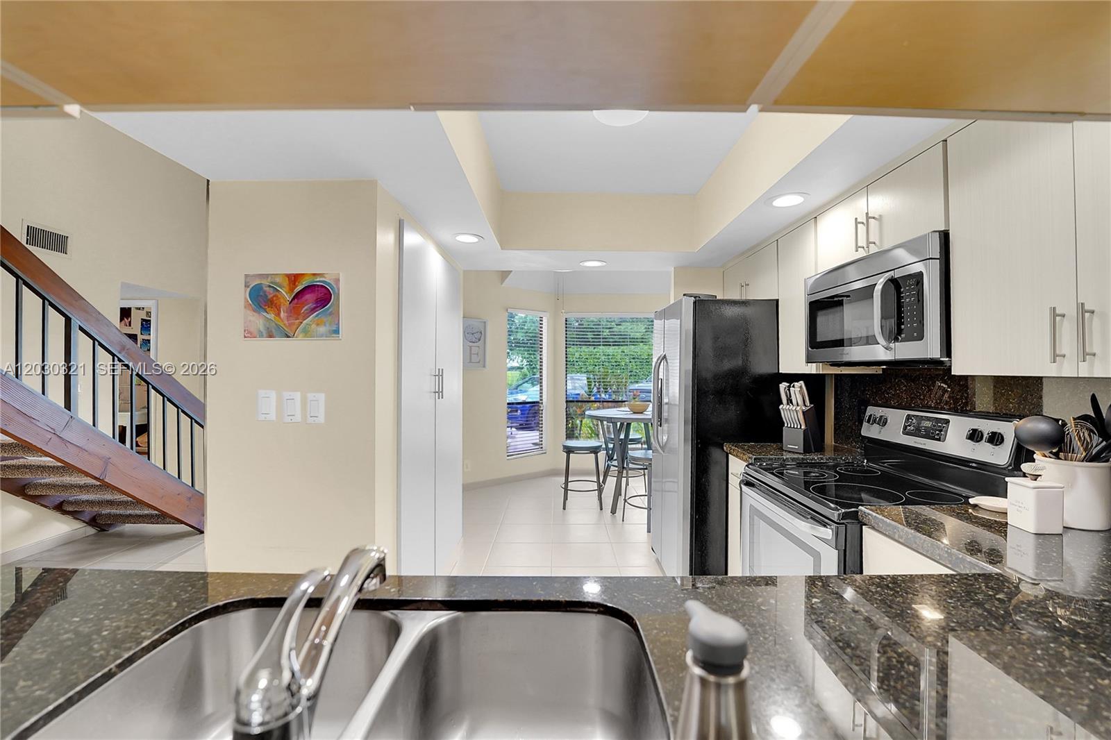 A kitchen with dark granite countertops, stainless steel appliances, and an adjacent dining area — 1400 NW 9th Ave # 18, Boca Raton FL 33486, BOCA RATON, FL