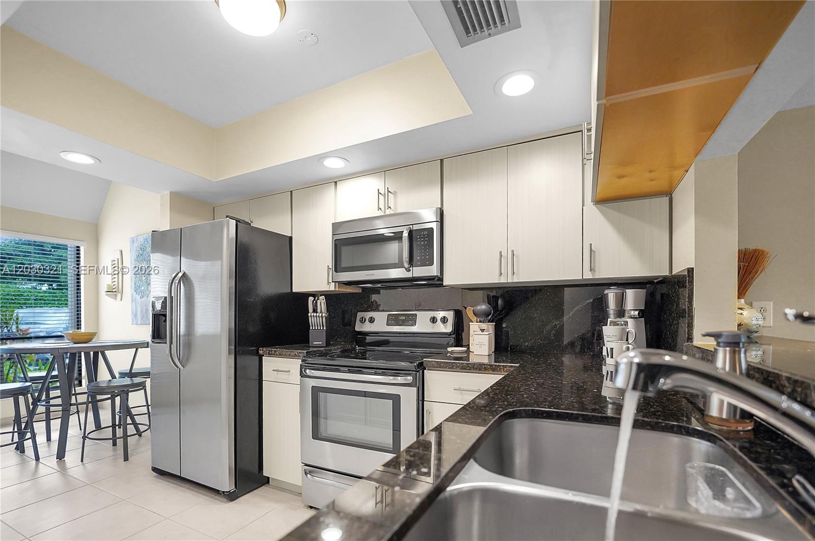 A kitchen features stainless steel appliances, light-colored cabinets, and dark granite countertops — 1400 NW 9th Ave # 18, Boca Raton FL 33486, BOCA RATON, FL